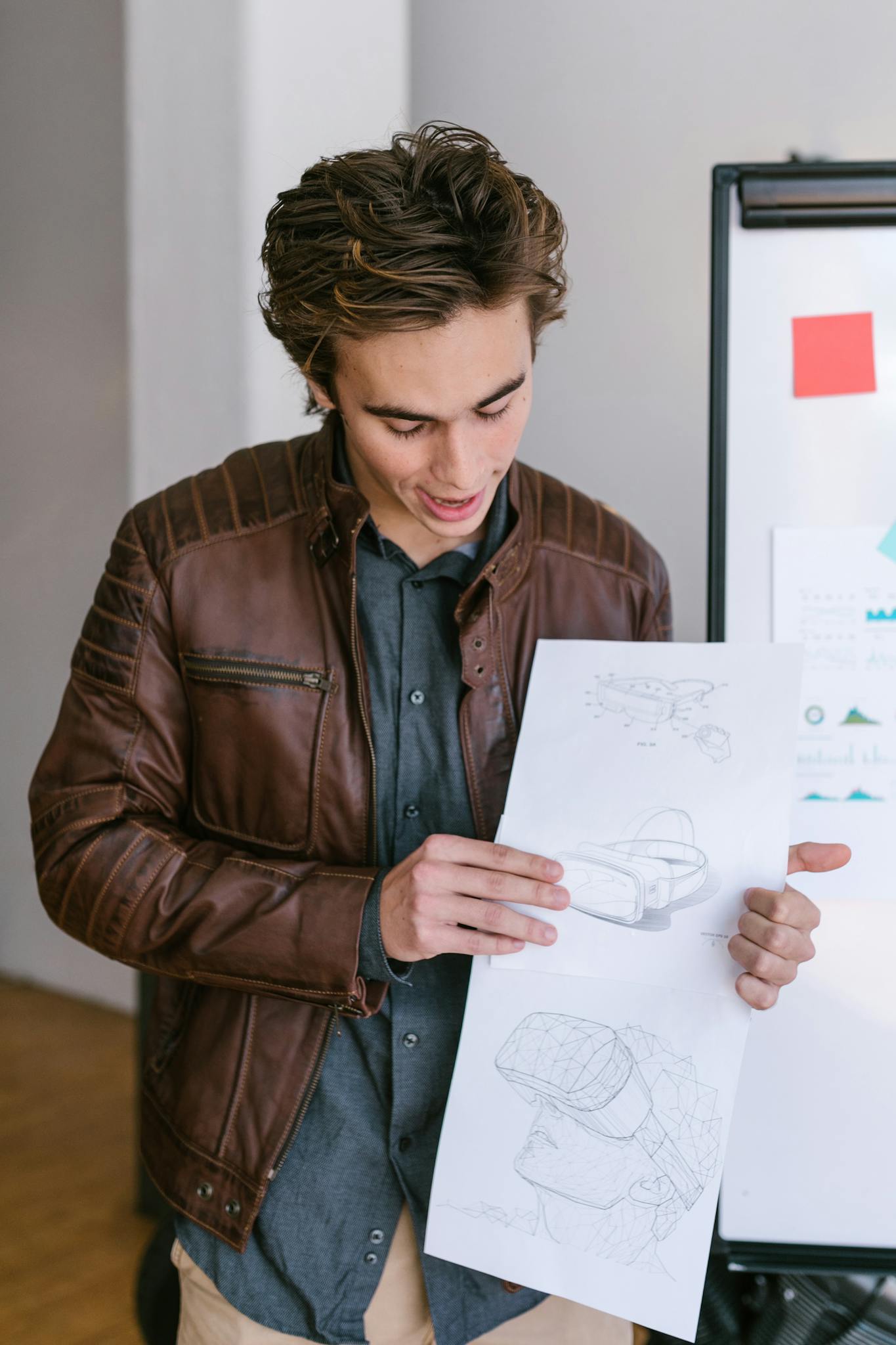 Adult man in casual attire presenting design sketches in a modern office.