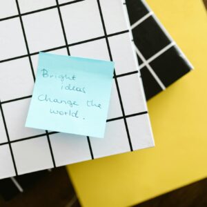 Blue sticky note with motivational quote on grid and solid colored notebooks.