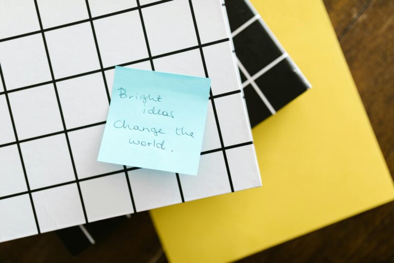 Blue sticky note with motivational quote on grid and solid colored notebooks.